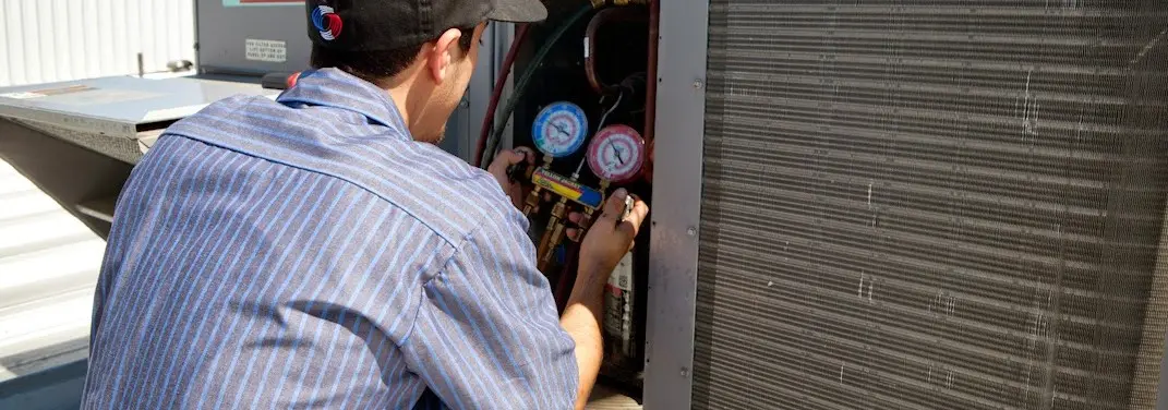 HVAC technician servicing a condenser unit in Groveland